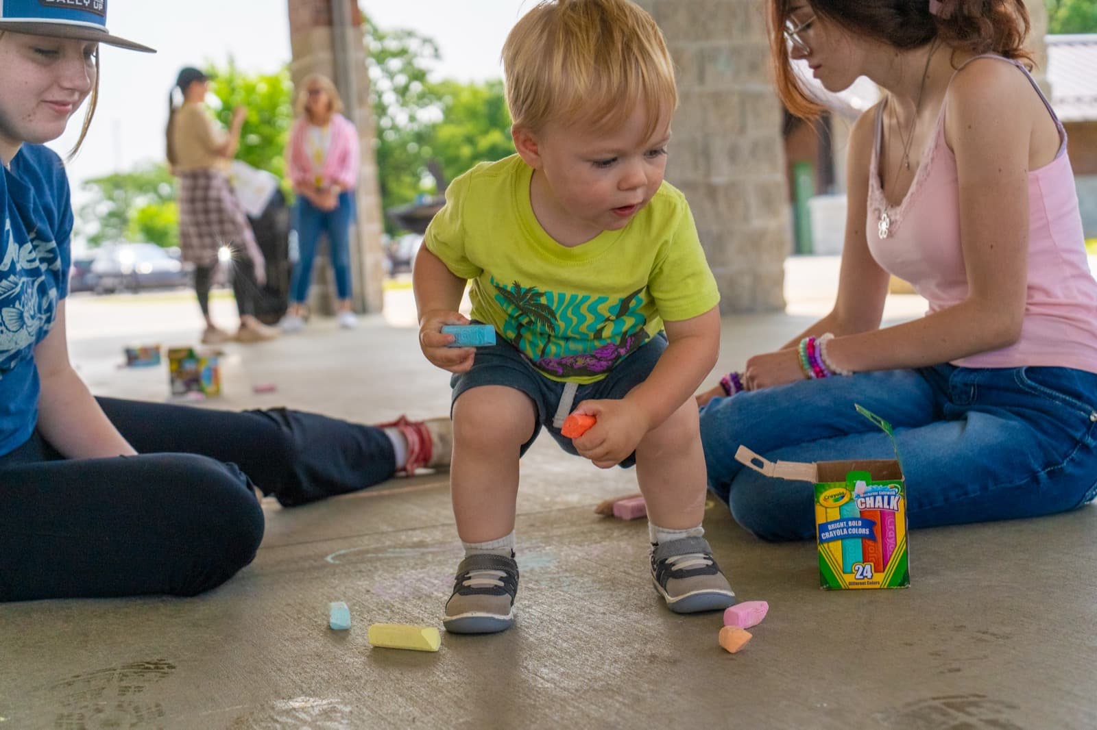 Children playing with activity toys on the grass at a community event.